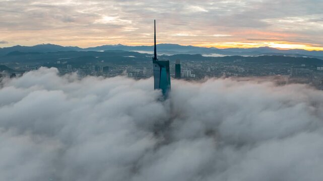 Aerial view time lapse 4k video of Kuala Lumpur city center view during dawn overlooking the city skyline in Federal Territory, Malaysia with epic low cloud glows on sunrise. Tilt up
