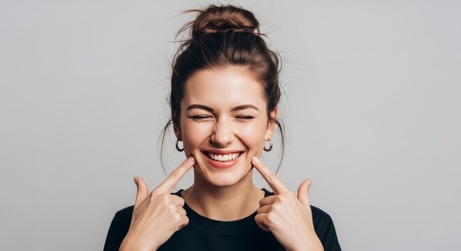 Young Woman Smiling Happily, Pointing to Cheeks with Fingers, Joyful Expression