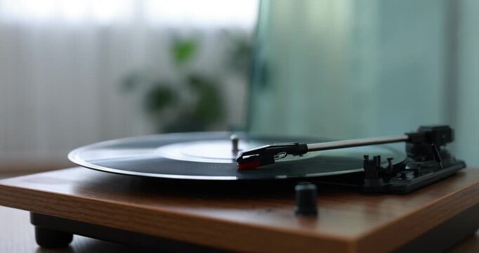 Modern turntable with vinyl record on table at home, closeup