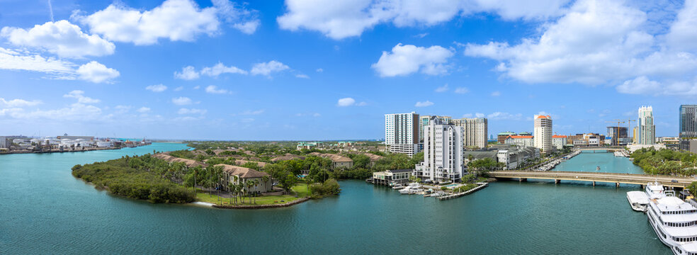 A wide panoramic view of the Tampa city skyline and waterfront harbor with residential buildings, bridges, and boats in Tampa, Florida, United States.