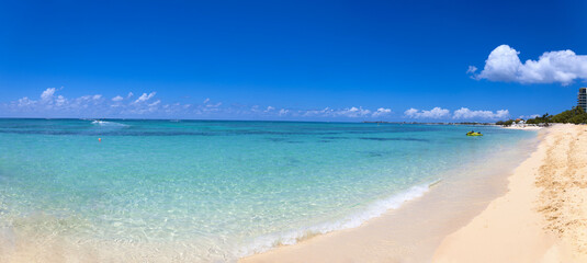 Obraz premium Wide panoramic view of the tropical Seven Mile Beach in George Town Grand Cayman featuring crystal clear turquoise water white sand and a bright blue sky