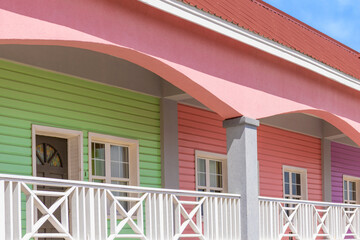 Naklejka premium Close-up of a vibrant multicolored Caribbean building with green, pink and purple painted wooden siding and white decorative balcony railing in Basseterre, St Kitts and Nevis