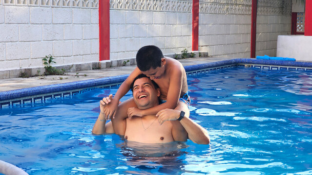 Divorced single dad and his 11-year-old Latino son play in the pool and teach him to swim during their vacation