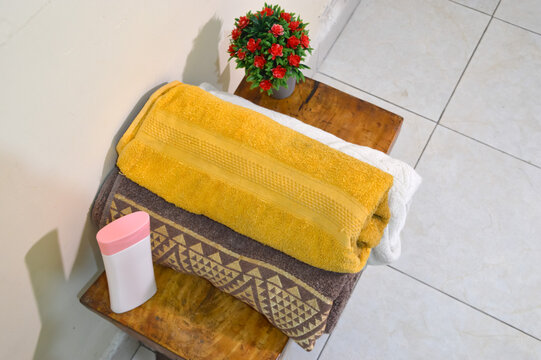 This extreme high angle perspective from the right side captures the organized layout of folded towels and grooming products on a curved tabletop with floral accents.