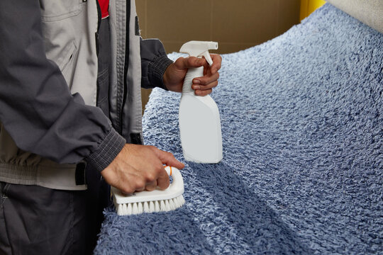 Man using spray to remove stain from carpet in carpet cleaning service