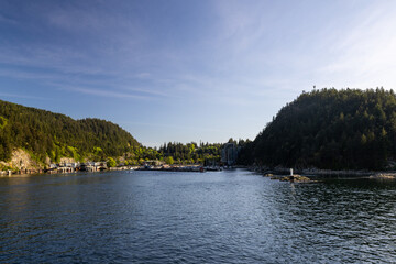 Fototapeta premium Scenic view of Snug Cove marina with boats and forested hills under a blue sky at Bowen Island British Columbia Canada