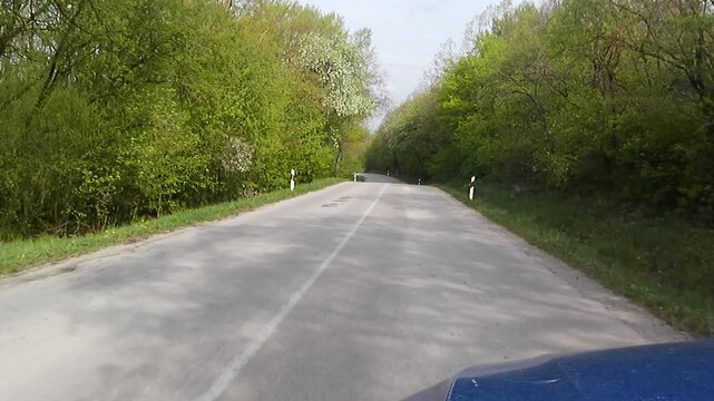 Spring local road ride across forested upland area of Myjava region, near Prasnik - Grnca vilalge. Mostly broadleaf spring forest with growing green foliage visible around, some white flowering trees