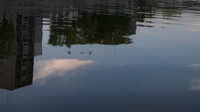 Evening sky and building reflections on calm river water, silent abstract background footage
