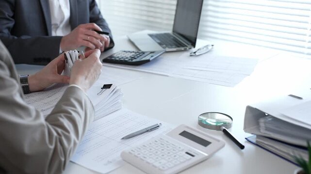 Business people reviewing financial documents, calculating tax, auditing corporate accounting records, and processing paperwork in office. Audit and taxes in business