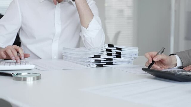 Professionals handling a large stack of documents and paperwork, signing a contract in a busy office. Audit and taxes in business