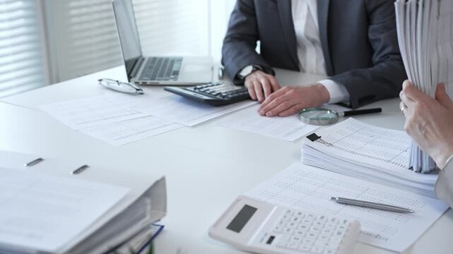 Business people reviewing financial documents, calculating tax, auditing corporate accounting records, and processing paperwork in office. Audit and taxes in business