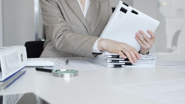 Businesswoman hands organizing stack of papers with binder clips, working on financial documents and official reports in office. Audit and taxes concept