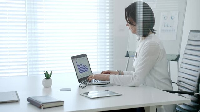 Professional woman crunching numbers and analyzing financial data on a laptop in a bright modern office, planning business strategies and managing growth