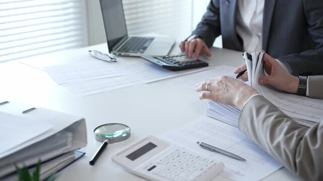 Business people reviewing financial documents, calculating tax, auditing corporate accounting records, and processing paperwork in office. Audit and taxes in business