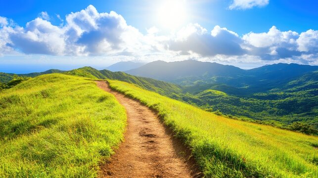 A sunlit mountain hiking trail winds through lush green hills towards a hazy horizon, offering breathtaking scenic vistas.