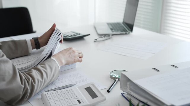 Businesswoman hands organizing stack of papers with binder clips, working on financial documents and official reports in office. Audit and taxes concept