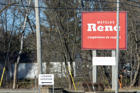 Quebec, Canada, 24 April 2026 : A red billboard for Matelas Rene displays its brand name and slogan 'L'experience du confort' next to a delivery sign.