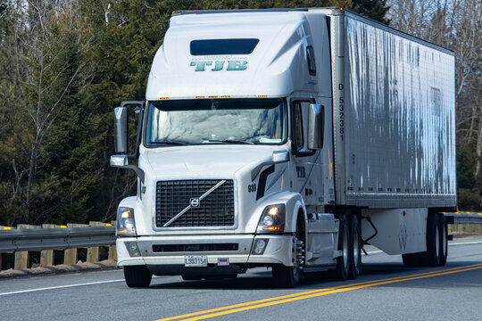 Quebec, Canada, 24 April 2026 : A white Volvo semi-truck with a TJB Transport trailer drives on a road.