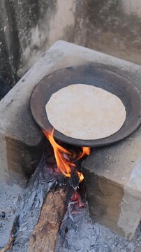Traditional Indian flatbread roti cooking on an iron tawa over a wood fire stove