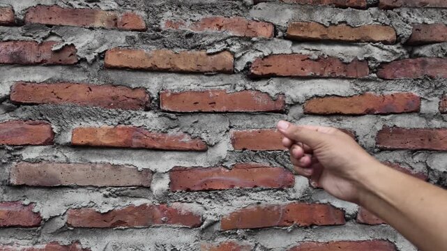 Wide macro footage of a rustic red brick wall under construction. The video highlights the uneven cement application and raw texture, perfect for construction, industrial.