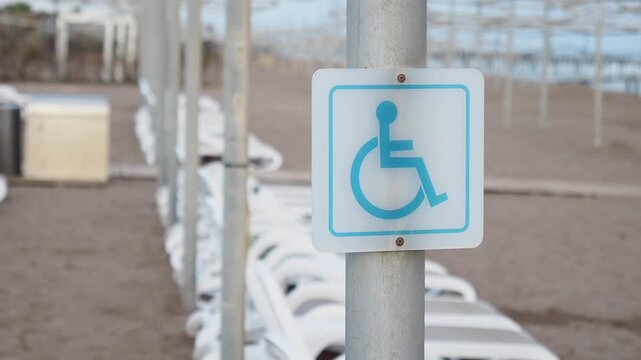 Beach access sign for disabled visitors near lounge chairs