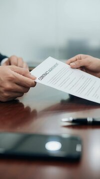 Hands passing contract agreement document on a table