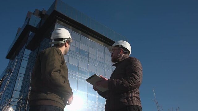 Two Engineers Outside Glass Office Tower Conclude Inspection With Handshake And Final Checks. Media