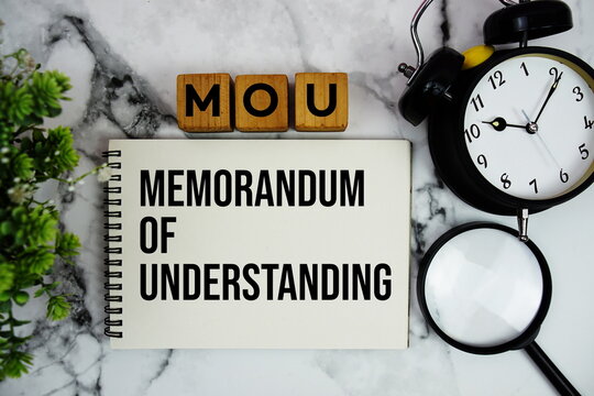 MOU Memorandum of Understanding text with alarm clock and magnifying glass on marble background