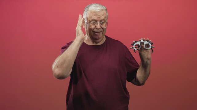 Man holding a trial frame phoropter while touching temple with hand during eye examination in studio; frustration vision test.