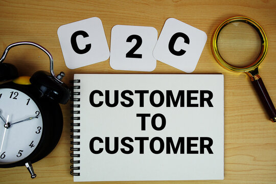 C2C Customer To Customer text written on notepad with magnifying glass and alarm clock on wooden background