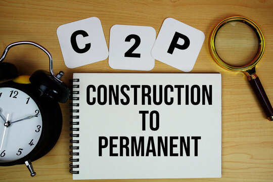 C to P Construction to Permanent Loan text written on notepad with magnifying glass and alarm clock on wooden background