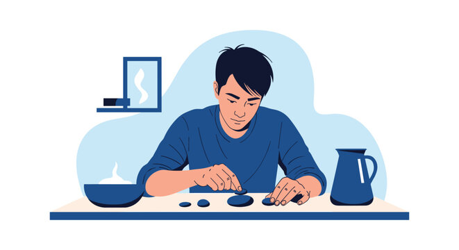 Man sitting at a table and carefully arranging small dark stones or pebbles representing mindfulness concentration and peaceful activities.