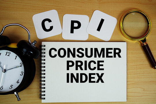 CPI Consumer Price Index text written on notepad with magnifying glass and alarm clock on wooden background