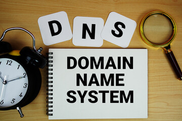 DNS Domain Name System text written on notepad with magnifying glass and alarm clock on wooden background © may1985