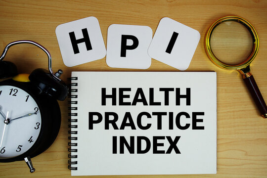 HPI Health Practice Index text written on notepad with magnifying glass and alarm clock on wooden background