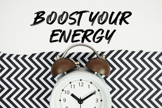 Boost Your Energytext written on paper rip with alarm clock flat lay on black chevron background