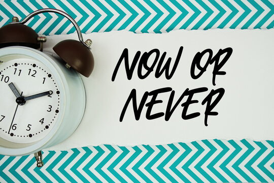 Now or Never text written on paper with alarm clock on green chevron background