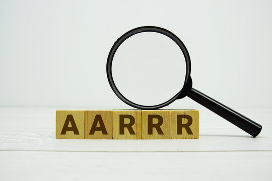 AARRR Acquisition, Activation, Retention, Referral, Revenue alphabet letters with magnifying glass on wooden background