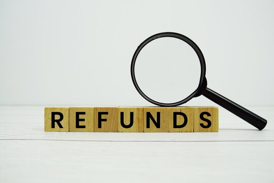 REFUNDS alphabet letters with magnifying glass on wooden background