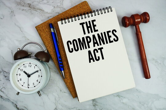 The Companies Act text written on notepad with pen, alarm clock and judge gavel on marble background