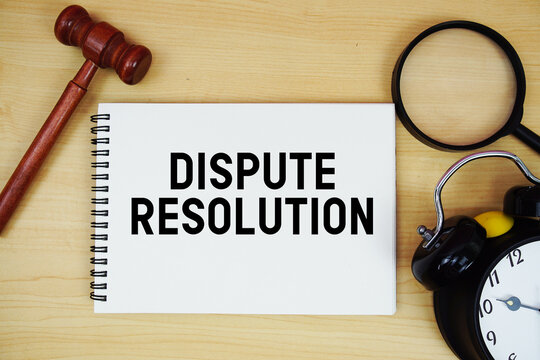 Dispute Resolution text written on notepad with pen, alarm clock and judge gavel on wooden background