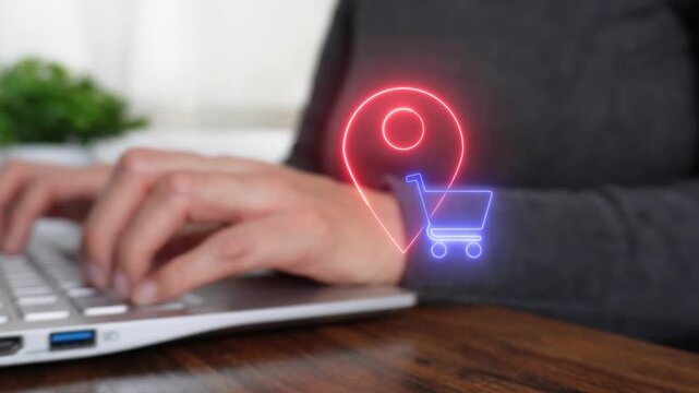 Close-up of a woman's hand working on a computer, pointing to a virtual location pin icon and a shopping cart.