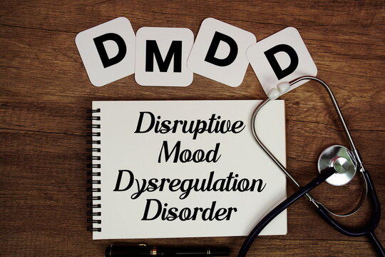 DMDD Disruptive Mood Dysregulation Disorder text written on notepad with stethoscope on wooden background
