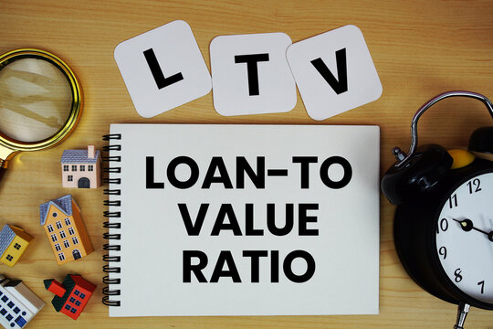 LTV Loan-to-Value Ratio text written on notepad with house model, alarm clock and magnifying glass on wooden background