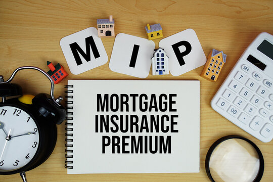 MIP Mortgage Insurance Premium text written on notepad with house model, alarm clock and magnifying glass on wooden background