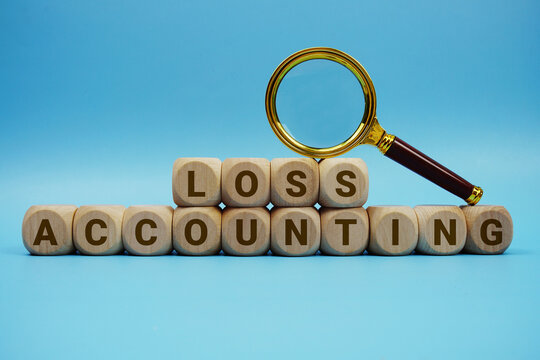 Loss Accounting alphabet letters wooden cube and magnifying glass on blue background