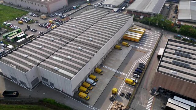Hyperlapse of yellow delivery vans departing warehouse ramps in Lombardy Italy. Active parcel distribution center handles morning dispatch and urban delivery operations.