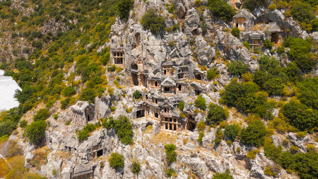 Demre, Turkey. Macro aerial view focusing on intricate carvings and architectural details of Lycian rock-cut tomb entrances. Aerial View