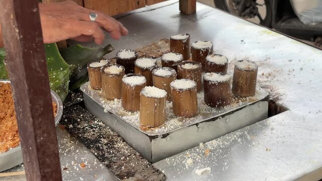 An Asian man selling traditional food checks the doneness of steamed Putu cake to ensure perfect texture a