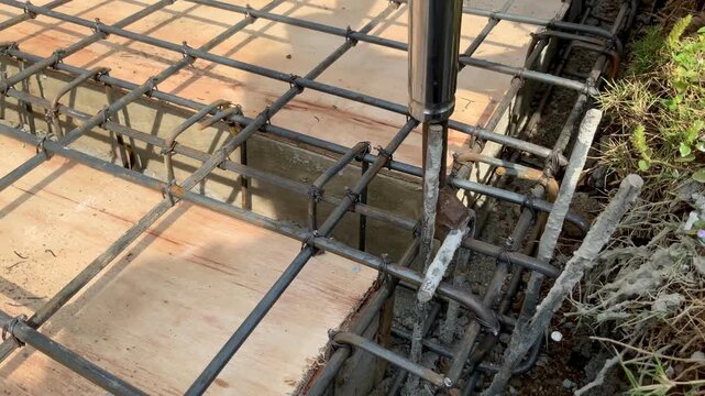 Construction worker using a manual rebar tying tool to secure steel reinforcement bars for concrete slab